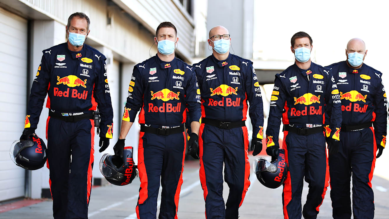 Red Bull mechanics and team personnel walk down the pitlane donning PPE