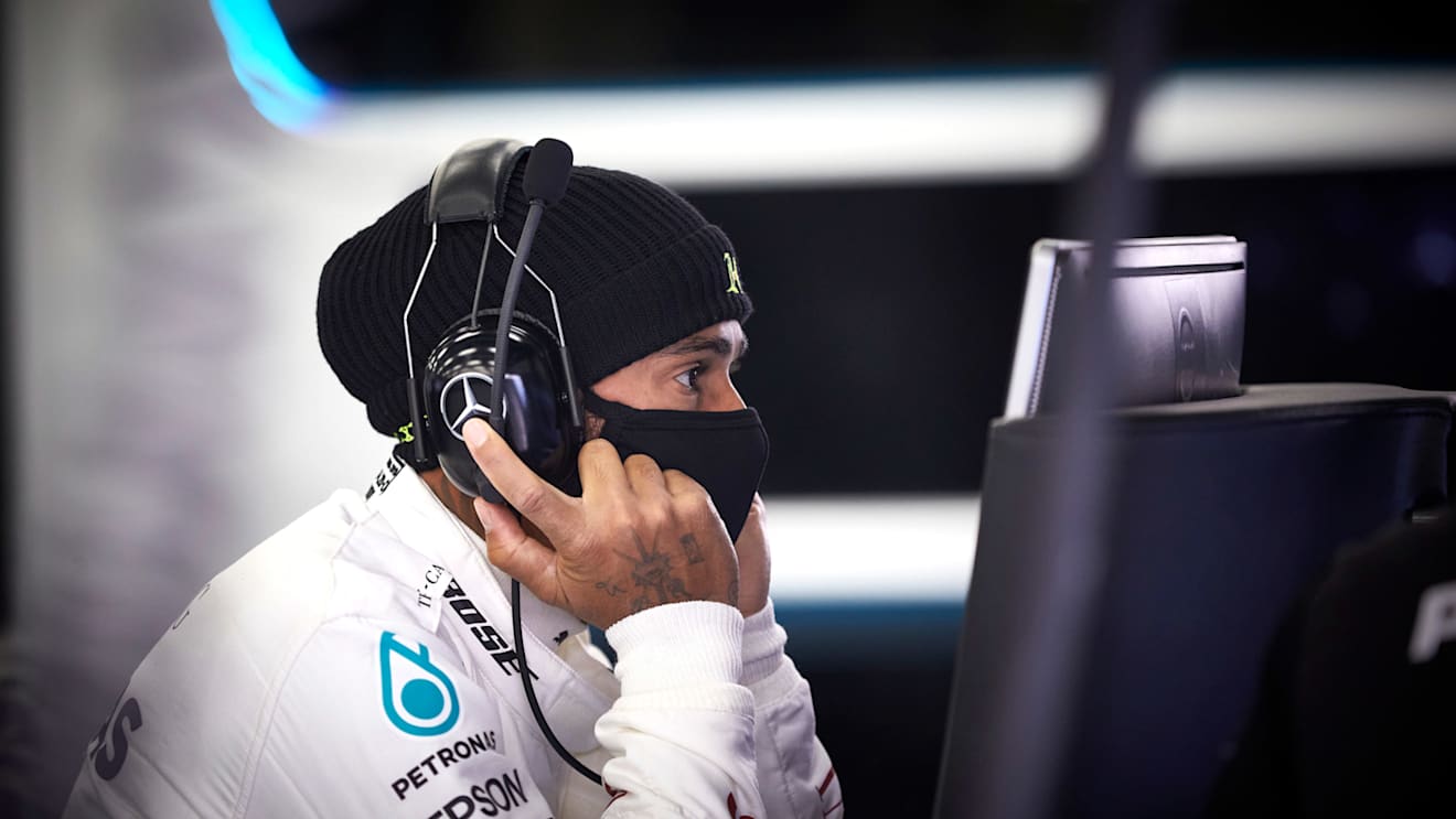 Lewis Hamilton wears a face mask as he looks over the data from his test on June 10