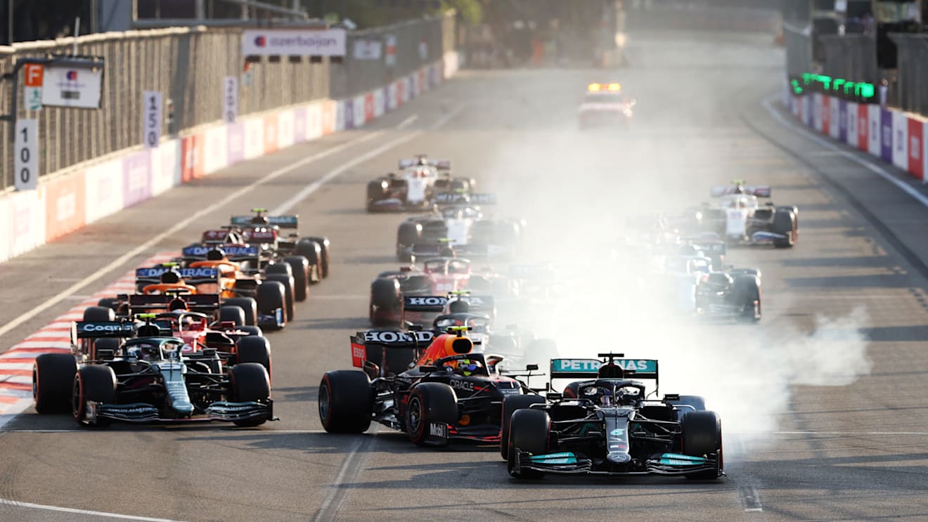 BAKU, AZERBAIJAN - JUNE 06: Lewis Hamilton of Great Britain driving the (44) Mercedes AMG Petronas F1 Team Mercedes W12 locks up under pressure from Sergio Perez of Mexico driving the (11) Red Bull Racing RB16B Honda into the first corner after the restart following a red flag period during the F1 Grand Prix of Azerbaijan at Baku City Circuit on June 06, 2021 in Baku, Azerbaijan. (Photo by Clive Rose/Getty Images)