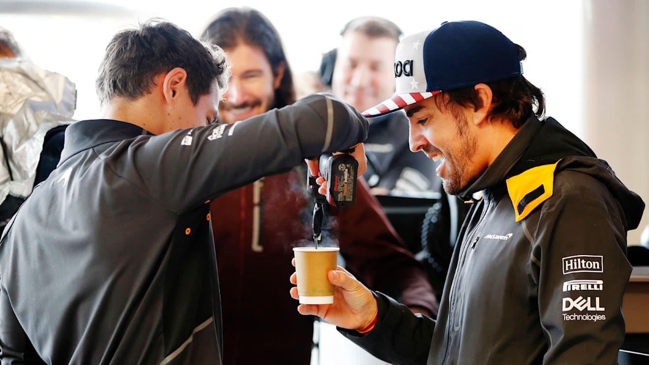 CIRCUIT OF THE AMERICAS, UNITED STATES OF AMERICA - OCTOBER 19: Lando Norris, McLaren, stirs a cup of tea with a power tool for Fernando Alonso, McLaren, as IndyCar driver JR Hildebrand watches in the garage during the United States GP at Circuit of the Americas on October 19, 2018 in Circuit of the Americas, United States of America. (Photo by Steven Tee / LAT Images)