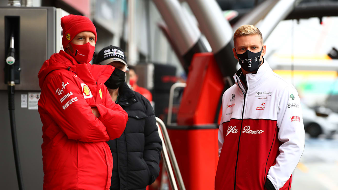 NUERBURG, GERMANY - OCTOBER 09: Sebastian Vettel of Germany and Ferrari and Mick Schumacher of Germany and Alfa Romeo Racing talk in the Pitlane during a weather delayed FP2 during practice ahead of the F1 Eifel Grand Prix at Nuerburgring on October 09, 2020 in Nuerburg, Germany. (Photo by Mark Thompson/Getty Images)