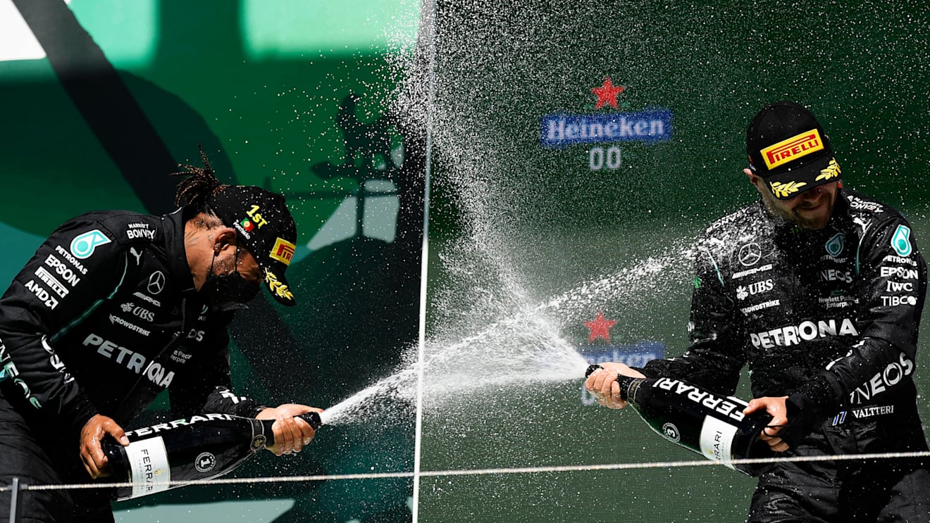 PORTIMAO, PORTUGAL - MAY 02: Race winner Lewis Hamilton of Great Britain and Mercedes GP and third placed Valtteri Bottas of Finland and Mercedes GP celebrate with sparkling wine on the podium after the F1 Grand Prix of Portugal at Autodromo Internacional Do Algarve on May 02, 2021 in Portimao, Portugal. (Photo by Gabriel Bouys - Pool/Getty Images)