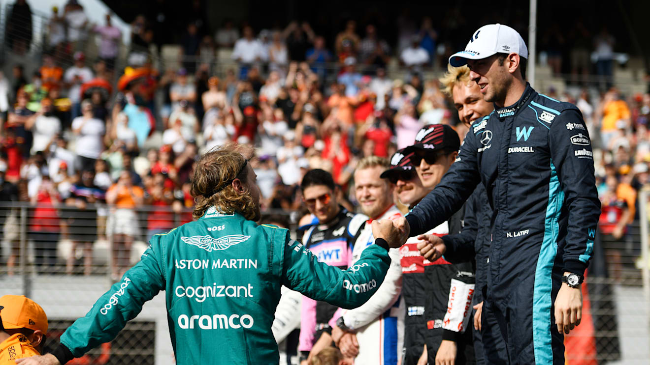 ABU DHABI, UNITED ARAB EMIRATES - NOVEMBER 20: Sebastian Vettel of Germany and Aston Martin F1 Team is greeted by Nicholas Latifi of Canada and Williams  as they prepare for the F1 2022 End of Year photo prior to the F1 Grand Prix of Abu Dhabi at Yas Marina Circuit on November 20, 2022 in Abu Dhabi, United Arab Emirates. (Photo by Rudy Carezzevoli/Getty Images)