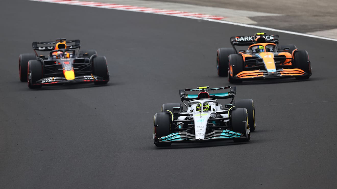 BUDAPEST, HUNGARY - JULY 31: Lewis Hamilton of Great Britain driving the (44) Mercedes AMG Petronas F1 Team W13 leads Max Verstappen of the Netherlands driving the (1) Oracle Red Bull Racing RB18 and Lando Norris of Great Britain driving the (4) McLaren MCL36 Mercedes during the F1 Grand Prix of Hungary at Hungaroring on July 31, 2022 in Budapest, Hungary. (Photo by Dan Istitene - Formula 1/Formula 1 via Getty Images)