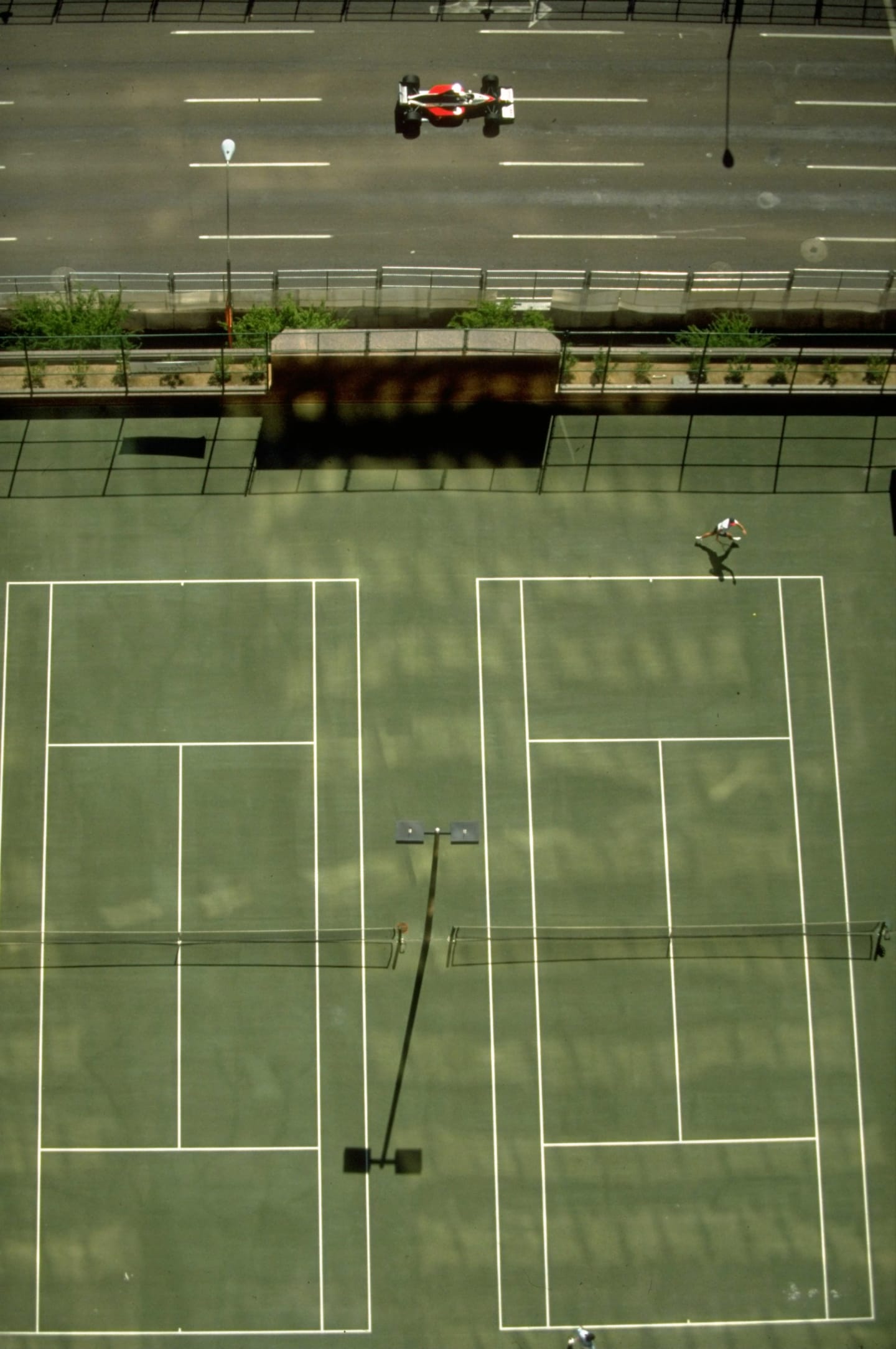 1991:  Aerial view of a Formula One car driving past tennis courts during the US Grand Prix at the