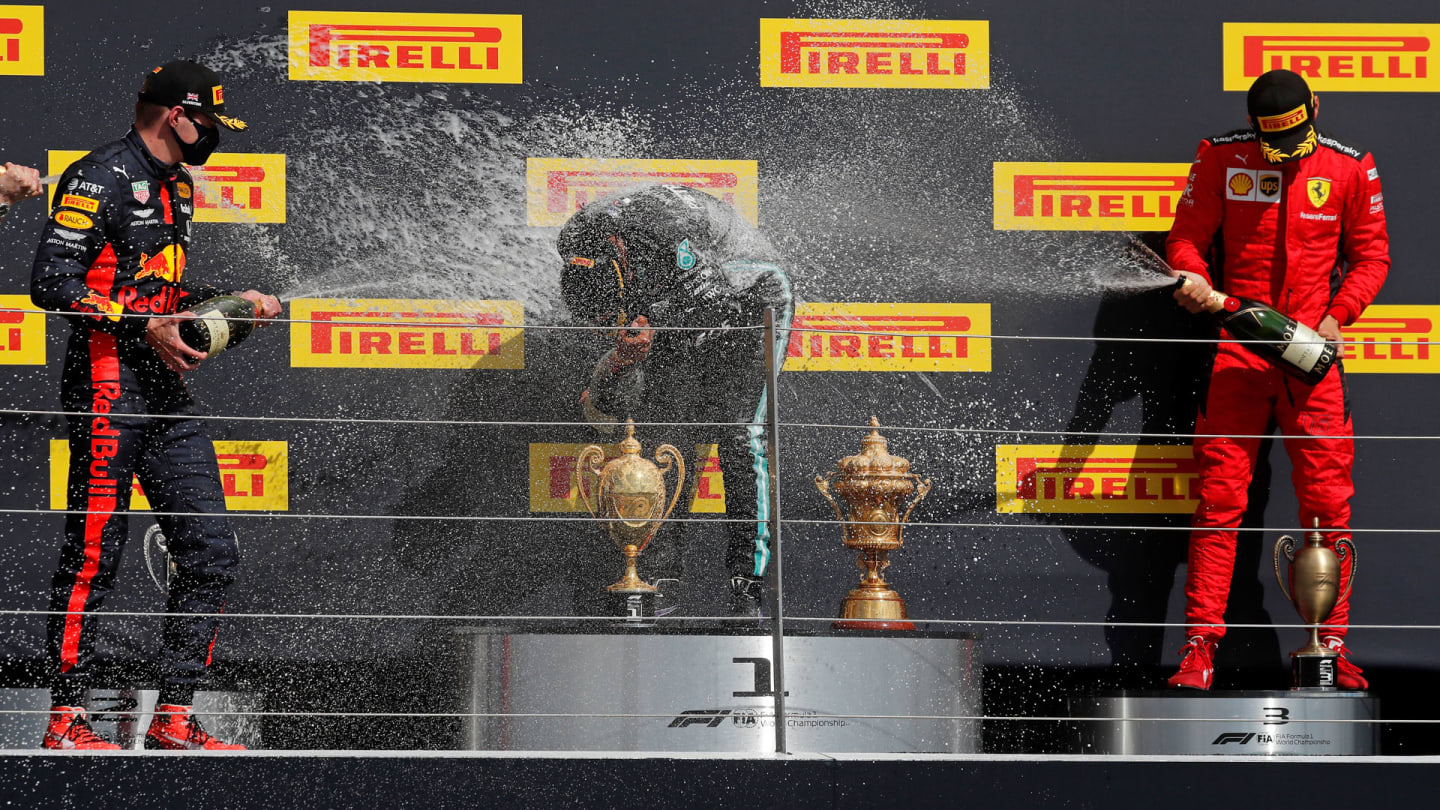 Mercedes' British driver Lewis Hamilton (C) is sprayed with champagne by second-placed Red Bull's