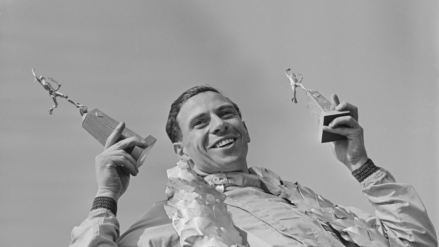British Formula One racing driver Jim Clark (1936-1968) celebrates on the podium with two