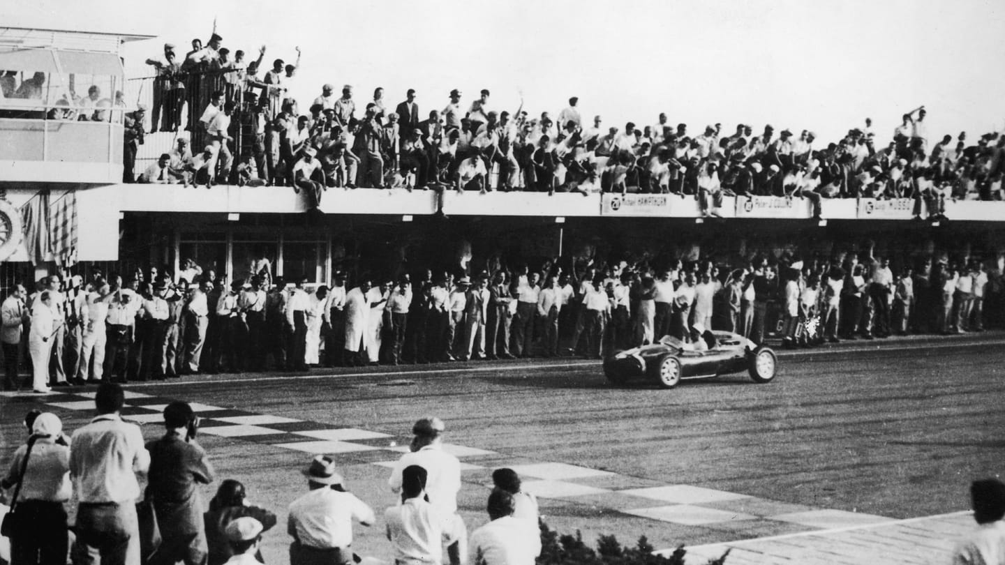 English racing driver Stirling Moss crosses the finishing line in a Cooper-Climax T43 to win the