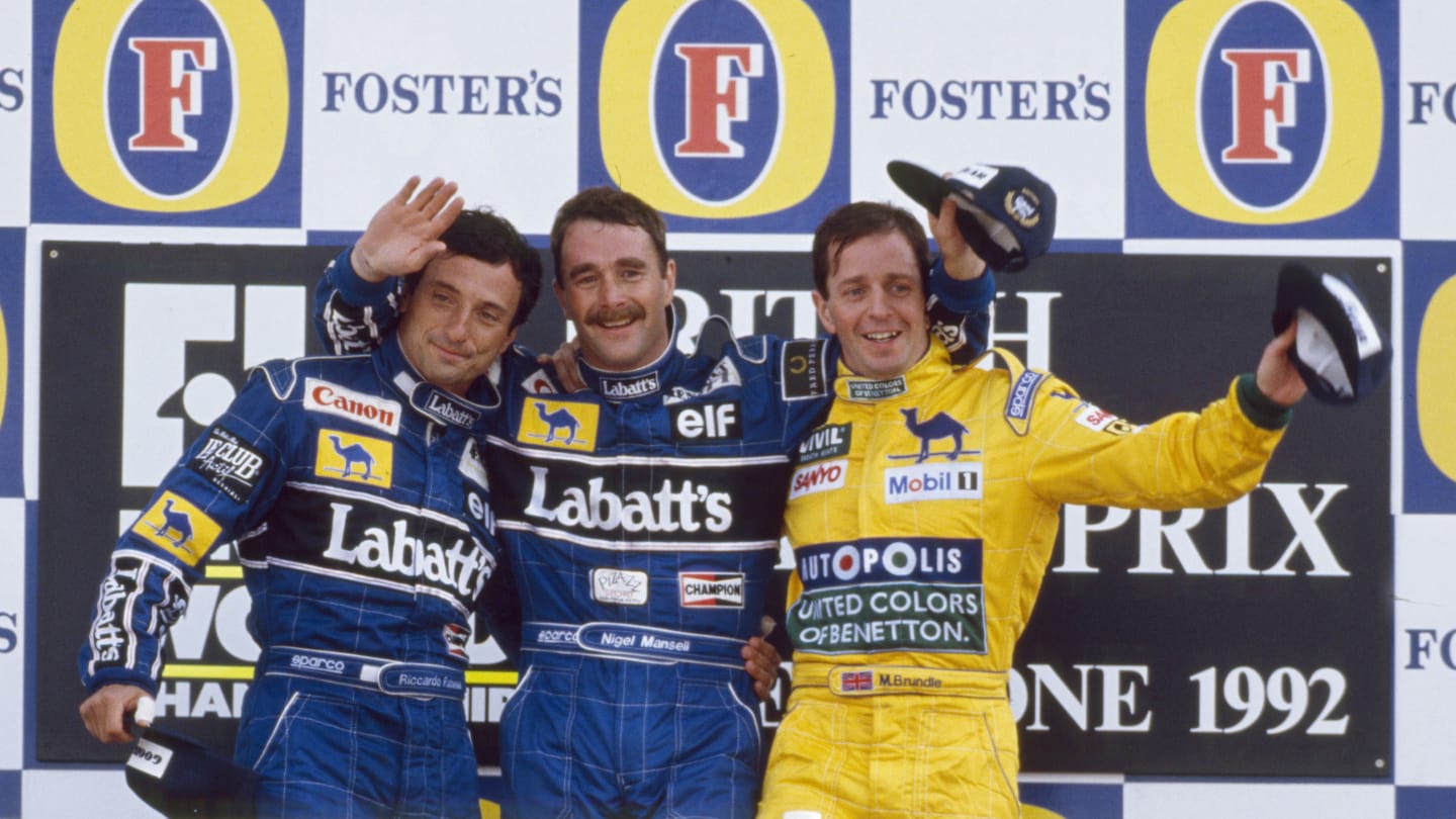 View of the winners of the 1992 British Grand Prix posed together on the podium, with from left,