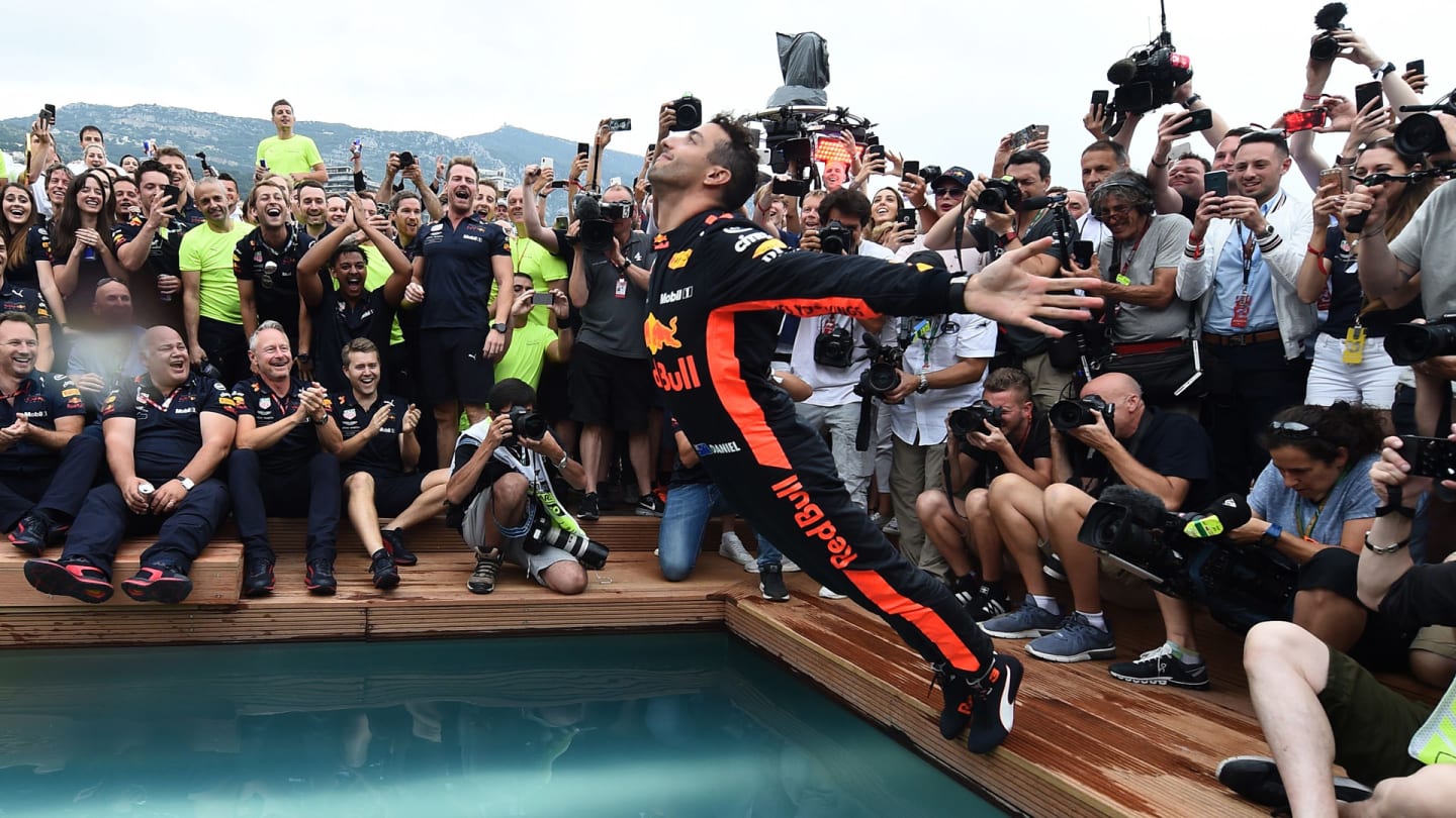 TOPSHOT - Red Bull Racing's Australian driver Daniel Ricciardo (C) jumps into a pool as he