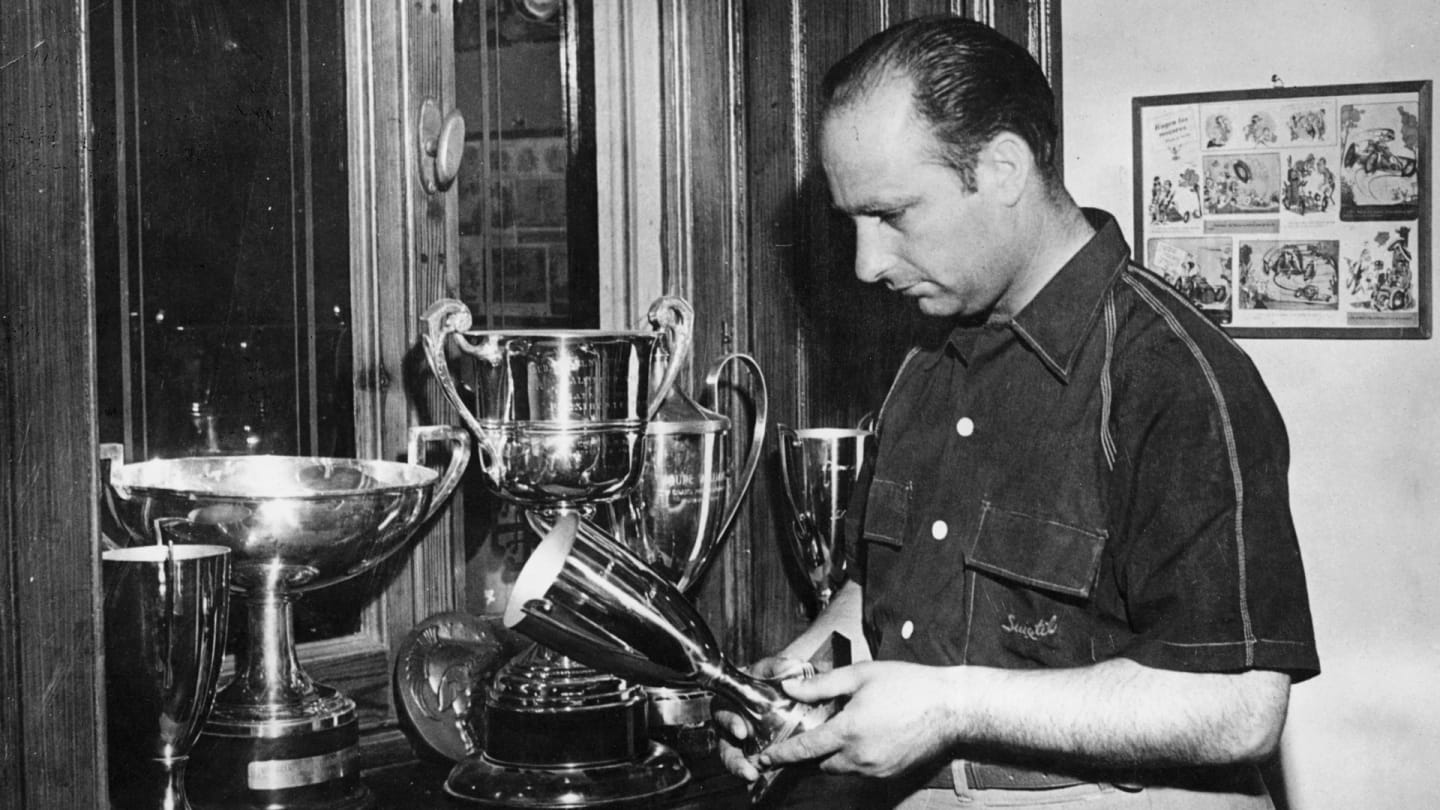 Juan Manuel Fangio, c1950. Fangio examining some of his motor racing trophies. In his Formula 1