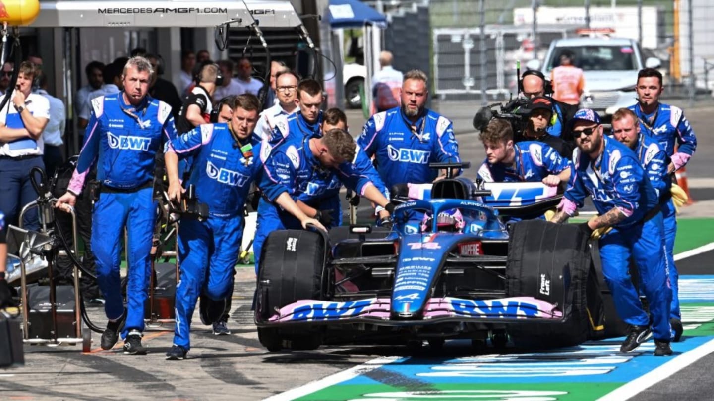 Mechanics move the car of Alpine's Spanish driver Fernando Alonso prior to the sprint qualifying at