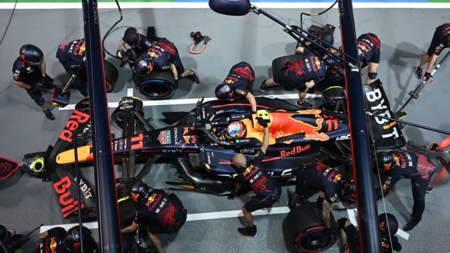 TOPSHOT - Mechanics work on the car of Red Bull Racing's Mexican driver Sergio Perez as he stops in