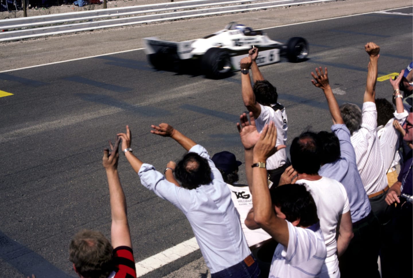 The Williams team celebrate as Keke Rosberg (FIN) Williams FW08 crosses the line to claim his first