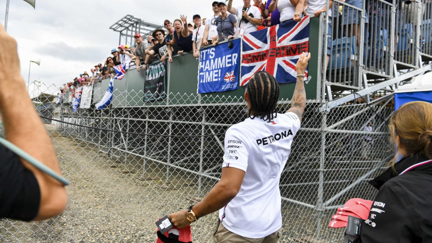 SILVERSTONE, UNITED KINGDOM - JULY 11: Lewis Hamilton, Mercedes AMG F1 gives hats to fans during