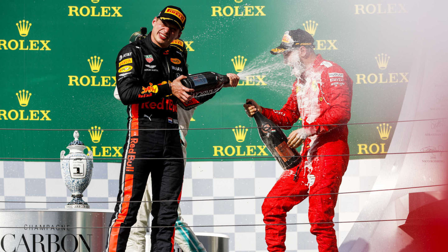 HUNGARORING, HUNGARY - AUGUST 04: Max Verstappen, Red Bull Racing, 2nd position, blasts Sebastian Vettel, Ferrari, 3rd position, with Champagne during the Hungarian GP at Hungaroring on August 04, 2019 in Hungaroring, Hungary. (Photo by Zak Mauger / LAT Images)