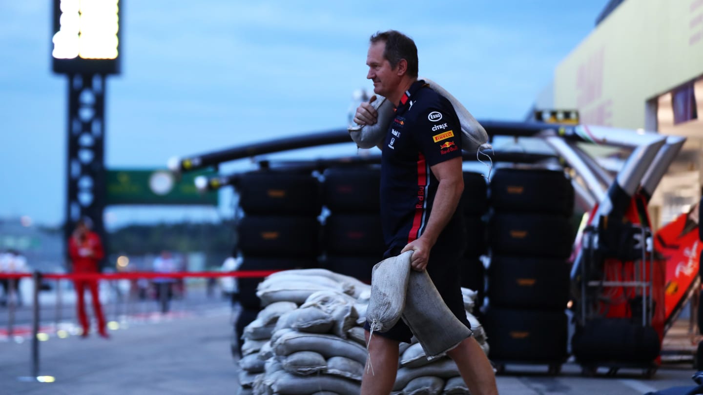 SUZUKA, JAPAN - OCTOBER 11: A Red Bull Racing team member moves sandbags in the Pitlane after