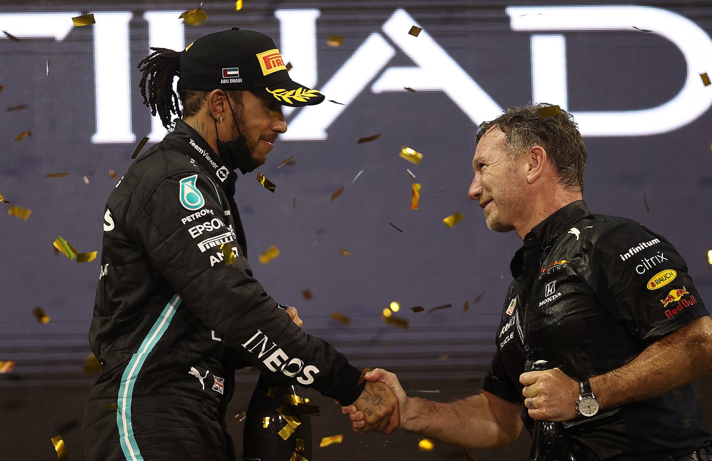 ABU DHABI, UNITED ARAB EMIRATES - DECEMBER 12: Red Bull Racing Team Principal Christian Horner shakes hands with second placed Lewis Hamilton of Great Britain and Mercedes GP on the podium during the F1 Grand Prix of Abu Dhabi at Yas Marina Circuit on December 12, 2021 in Abu Dhabi, United Arab Emirates. (Photo by Lars Baron/Getty Images)