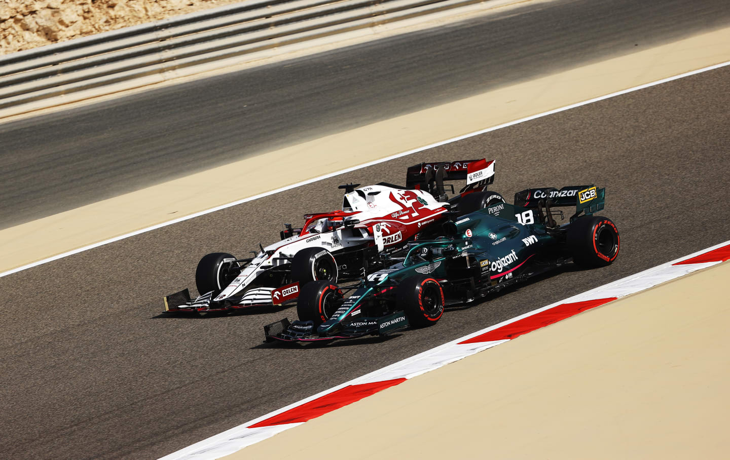 BAHRAIN, BAHRAIN - MARCH 26: Kimi Raikkonen of Finland driving the (7) Alfa Romeo Racing C41 Ferrari and Lance Stroll of Canada driving the (18) Aston Martin AMR21 Mercedes drive on track during practice ahead of the F1 Grand Prix of Bahrain at Bahrain International Circuit on March 26, 2021 in Bahrain, Bahrain. (Photo by Bryn Lennon/Getty Images)