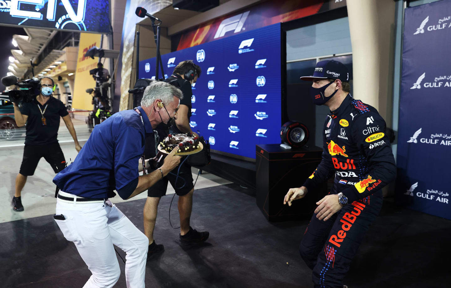 BAHRAIN, BAHRAIN - MARCH 27: Pole position qualifier Max Verstappen of Netherlands and Red Bull Racing puts a cake in the face of TV presenter and former racing driver David Coulthard in parc ferme during qualifying ahead of the F1 Grand Prix of Bahrain at Bahrain International Circuit on March 27, 2021 in Bahrain, Bahrain. (Photo by Lars Baron/Getty Images)