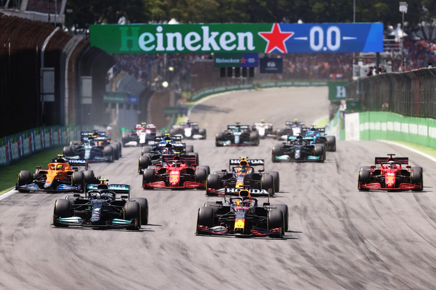 SAO PAULO, BRAZIL - NOVEMBER 14: Max Verstappen of the Netherlands driving the (33) Red Bull Racing RB16B Honda and Valtteri Bottas of Finland driving the (77) Mercedes AMG Petronas F1 Team Mercedes W12 lead the field into turn one at the start during the F1 Grand Prix of Brazil at Autodromo Jose Carlos Pace on November 14, 2021 in Sao Paulo, Brazil. (Photo by Lars Baron/Getty Images)