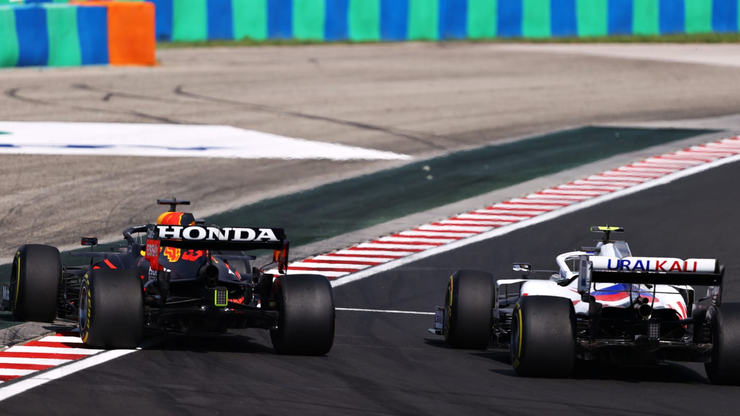 BUDAPEST, HUNGARY - AUGUST 01: Max Verstappen of the Netherlands driving the (33) Red Bull Racing RB16B Honda runs wide as he overtakes Mick Schumacher of Germany driving the (47) Haas F1 Team VF-21 Ferrari during the F1 Grand Prix of Hungary at Hungaroring on August 01, 2021 in Budapest, Hungary. (Photo by Bryn Lennon/Getty Images)