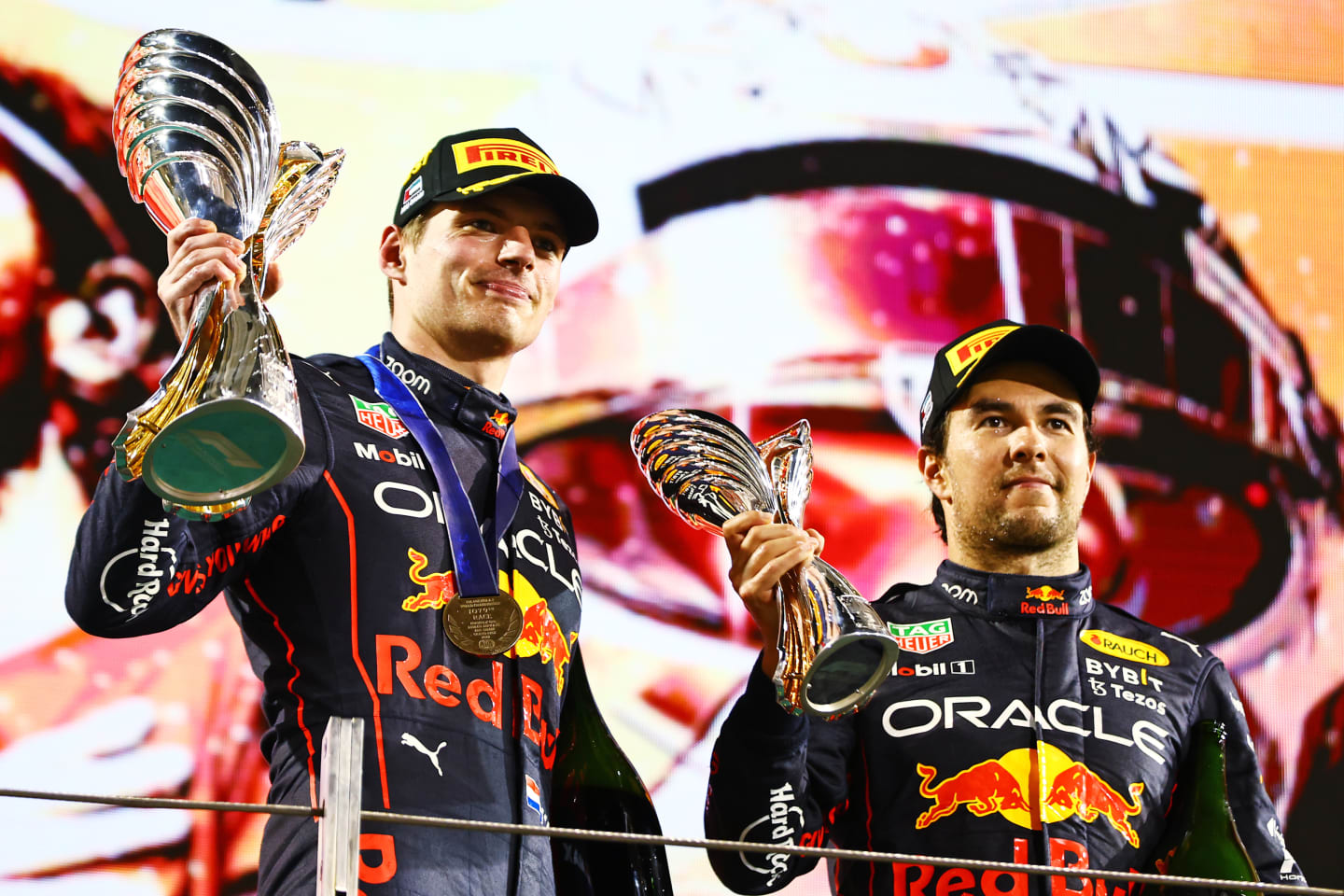 ABU DHABI, UNITED ARAB EMIRATES - NOVEMBER 20: Race Winner Max Verstappen of the Netherlands and Oracle Red Bull Racing and Third placed Sergio Perez of Mexico and Oracle Red Bull Racing celebrate on the podium during the F1 Grand Prix of Abu Dhabi at Yas Marina Circuit on November 20, 2022 in Abu Dhabi, United Arab Emirates. (Photo by Mark Thompson/Getty Images)