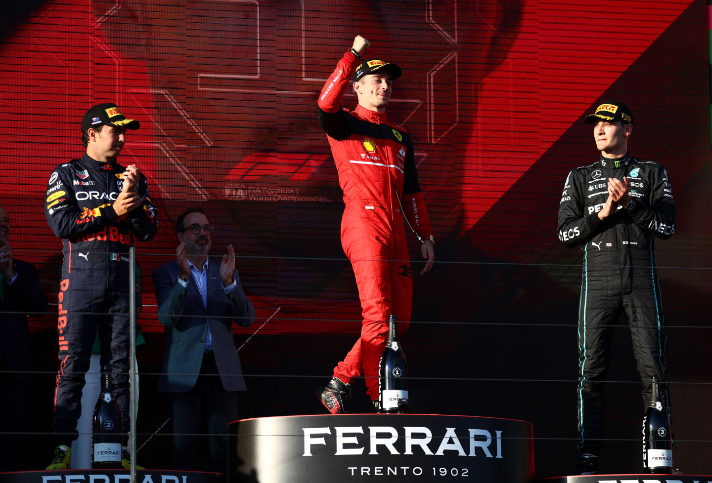 MELBOURNE, AUSTRALIA - APRIL 10: Race winner Charles Leclerc of Monaco and Ferrari celebrates on the podium next to Second placed Sergio Perez of Mexico and Oracle Red Bull Racing and Third placed George Russell of Great Britain and Mercedes during the F1 Grand Prix of Australia at Melbourne Grand Prix Circuit on April 10, 2022 in Melbourne, Australia. (Photo by Bryn Lennon - Formula 1/Formula 1 via Getty Images)
