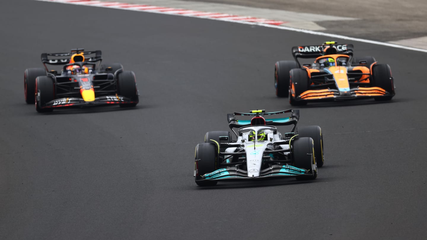 BUDAPEST, HUNGARY - JULY 31: Lewis Hamilton of Great Britain driving the (44) Mercedes AMG Petronas F1 Team W13 leads Max Verstappen of the Netherlands driving the (1) Oracle Red Bull Racing RB18 and Lando Norris of Great Britain driving the (4) McLaren MCL36 Mercedes during the F1 Grand Prix of Hungary at Hungaroring on July 31, 2022 in Budapest, Hungary. (Photo by Dan Istitene - Formula 1/Formula 1 via Getty Images)