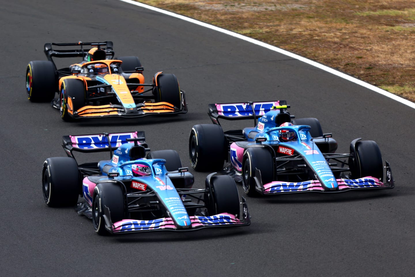 BUDAPEST, HUNGARY - JULY 31: Fernando Alonso of Spain driving the (14) Alpine F1 A522 Renault, Esteban Ocon of France driving the (31) Alpine F1 A522 Renault and Daniel Ricciardo of Australia driving the (3) McLaren MCL36 Mercedes battle for track position during the F1 Grand Prix of Hungary at Hungaroring on July 31, 2022 in Budapest, Hungary. (Photo by Dan Istitene - Formula 1/Formula 1 via Getty Images)