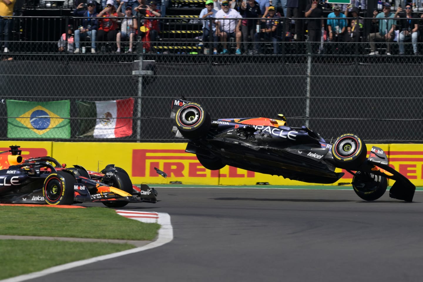 TOPSHOT - Red Bull Racing's Mexican driver Sergio Perez (R) crashes during the start of the Formula
