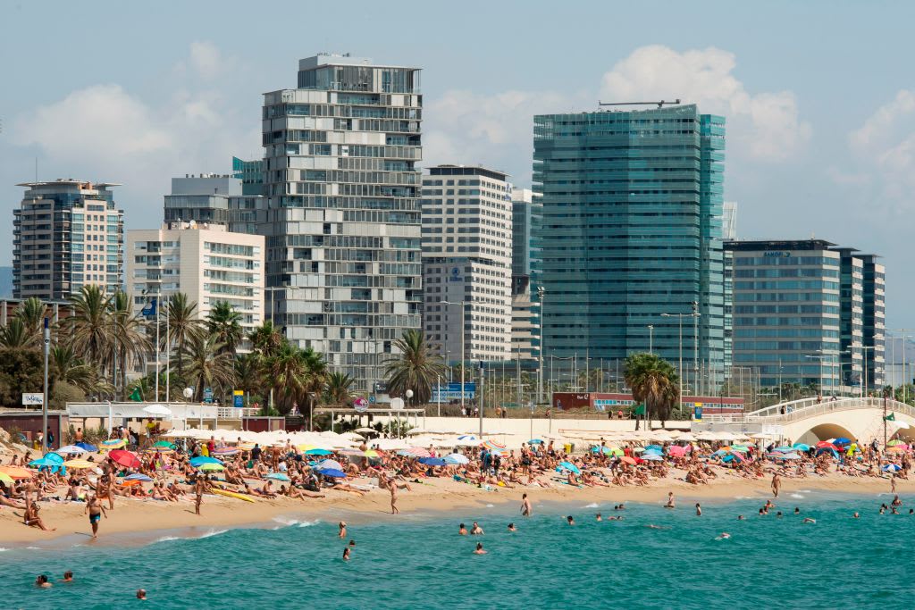People swim in the sea and sunbathe on Mar Bella beach in the Catalonian coastal city of Barcelona,