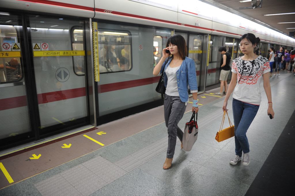 Two women walk down the platform after alighting from a subway train in Shanghai on June 27, 2012.