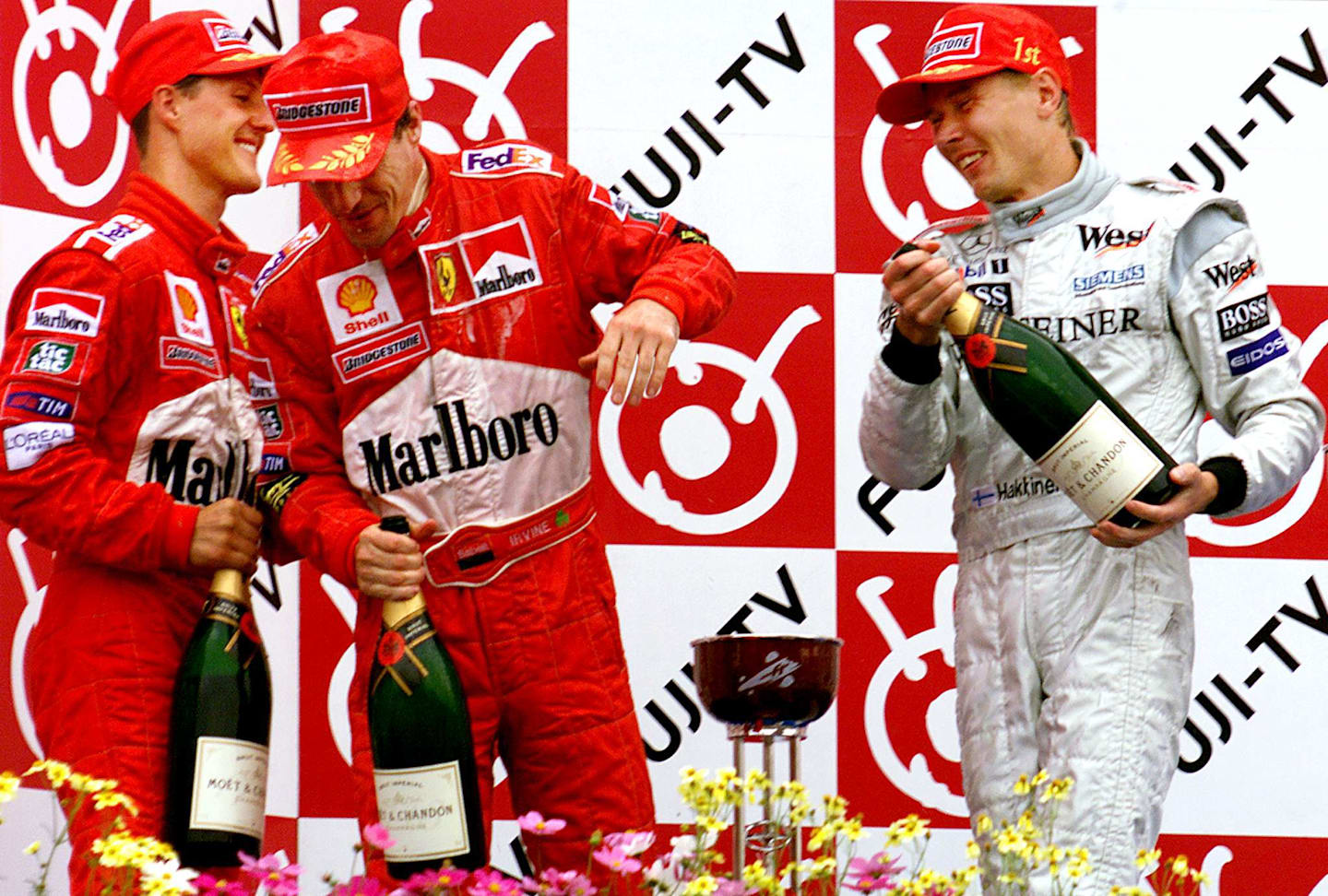 Finnish driver Mika Hakkinen (R) of Mclaren Mercedes splashes champagne to Ferrari drivers Eddie