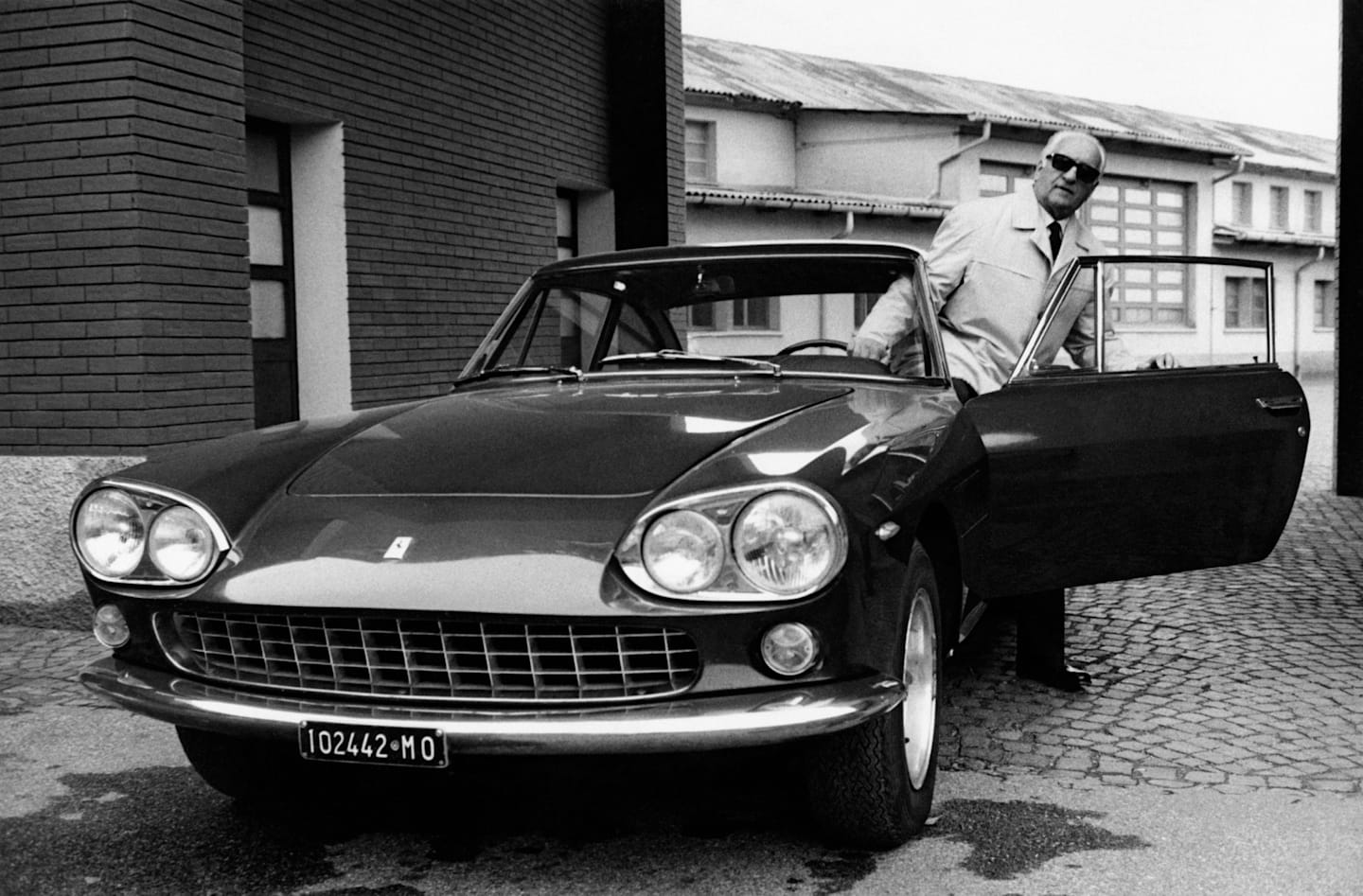 Italian entrepreneur and racing driver Enzo Ferrari getting off a car by his car manufacturer. 1966