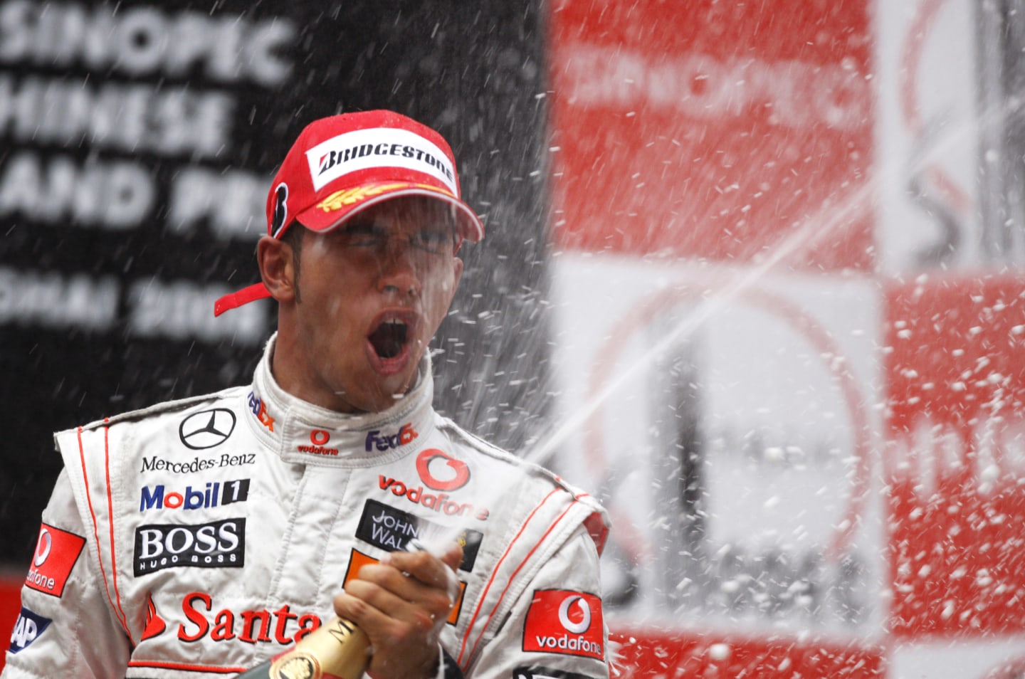 British McLaren Formula One driver Lewis Hamilton celebrates on the winners podium by spraying