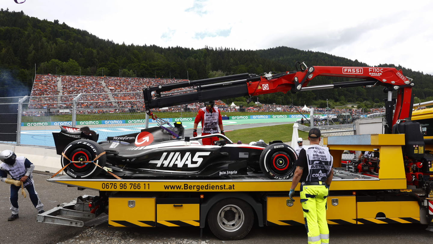 Workers lift the car of Haas F1 Team's German driver Nico Hulkenberg off the track during the
