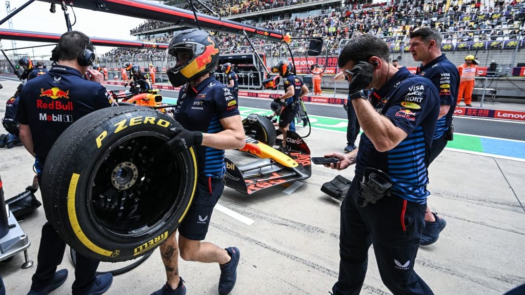 Crew members work on the car of Red Bull Racing's Mexican driver Sergio Perez in the pits during
