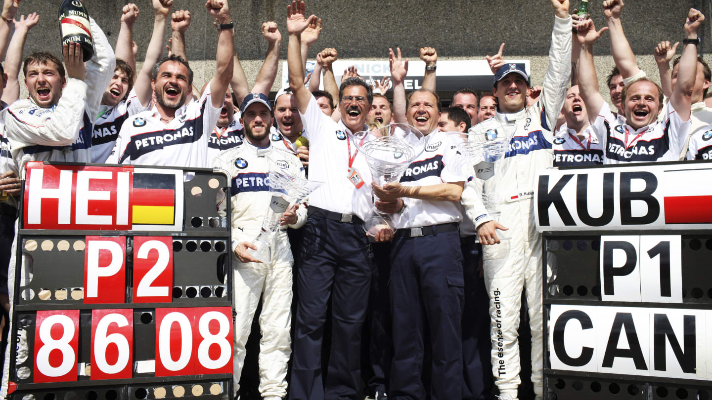 BMW Sauber team members Nick Heidfeld (centre left blue cap), Mario Theissen (centre left holding