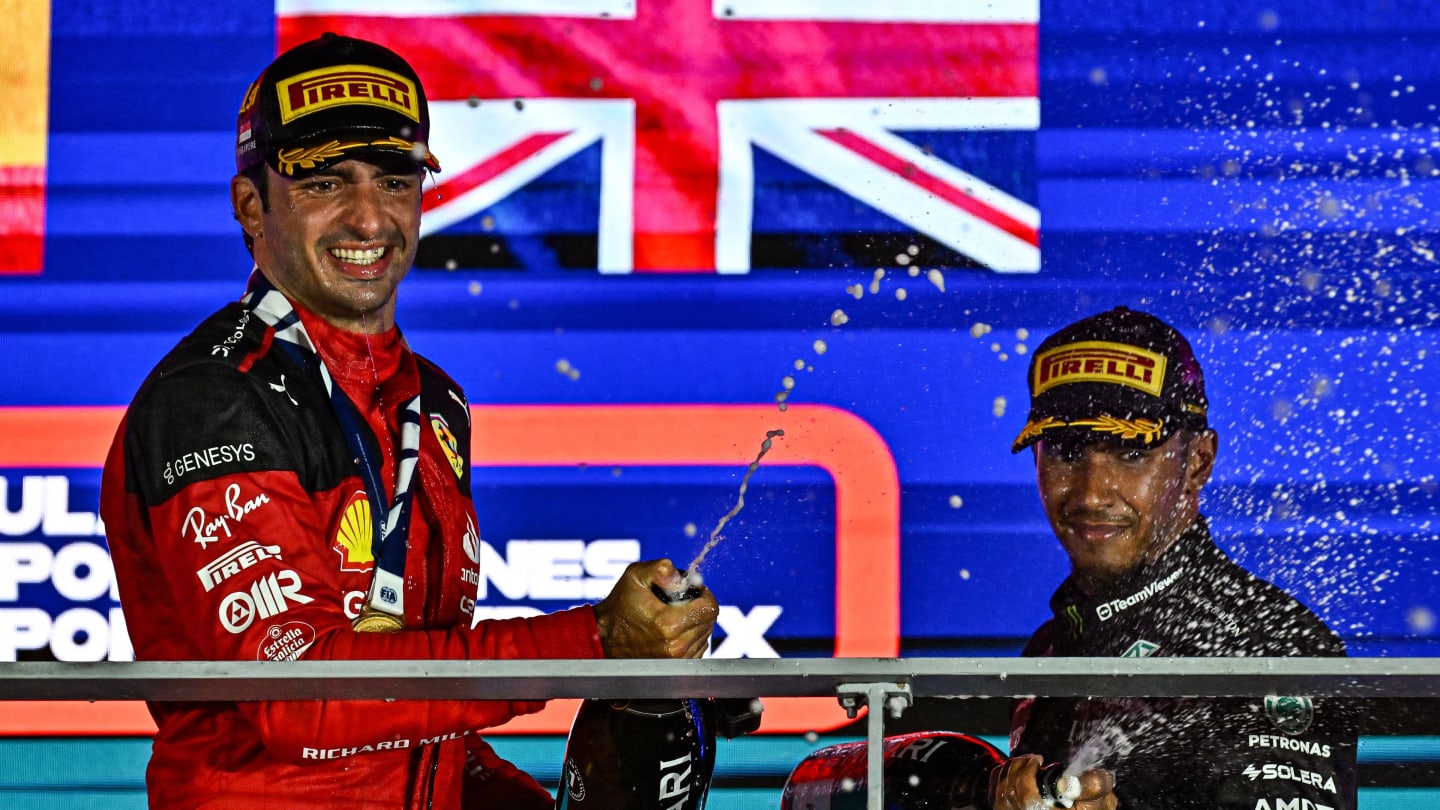 Ferrari's Spanish driver Carlos Sainz Jr (L) sprays champagne as he celebrates on the podium after