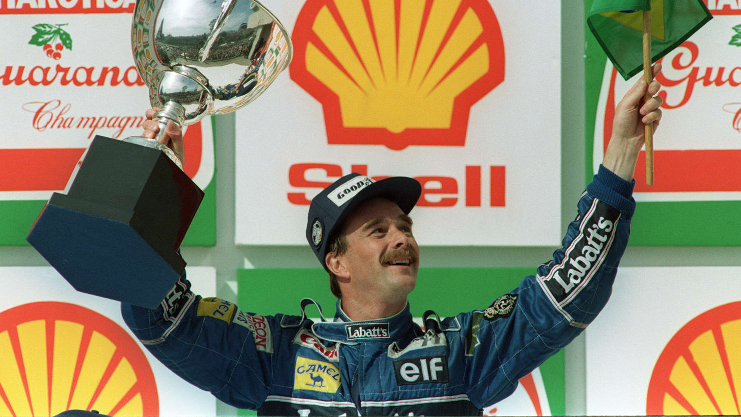British F-1 driver Nigel Mansell of the Williams-Renault team holds the Brazilian flag and the