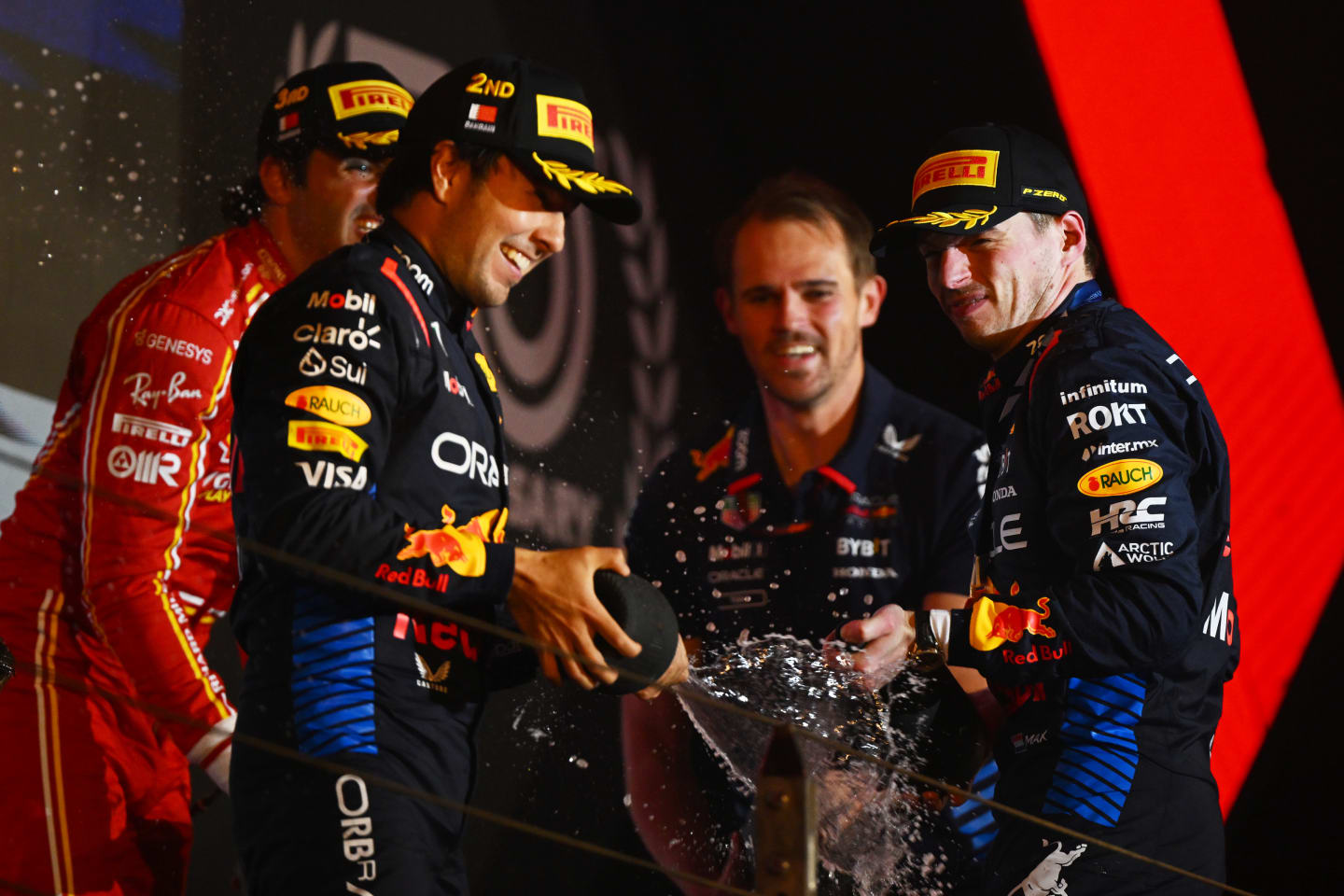 BAHRAIN, BAHRAIN - MARCH 02: Race winner Max Verstappen of the Netherlands and Oracle Red Bull Racing, Second placed Sergio Perez of Mexico and Oracle Red Bull Racing, Third placed Carlos Sainz of Spain and Ferrari and Tom Hart, Performance Engineer at Oracle Red BullÂ Racing celebrate on the podium during the F1 Grand Prix of Bahrain at Bahrain International Circuit on March 02, 2024 in Bahrain, Bahrain. (Photo by Clive Mason/Getty Images)