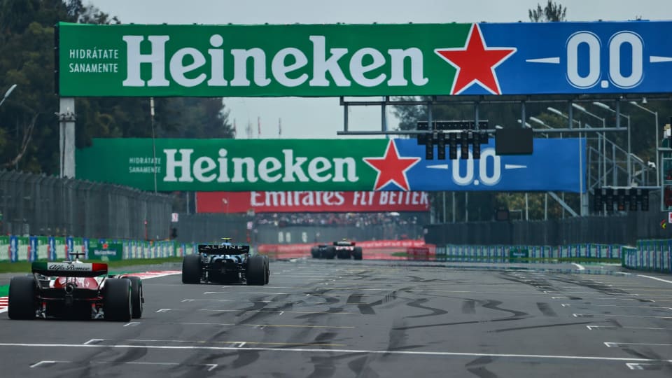 Formula 1 race cars on a track featuring prominent Heineken sponsorship banners, highlighting brand visibility and partnership during an F1 Grand Prix event.