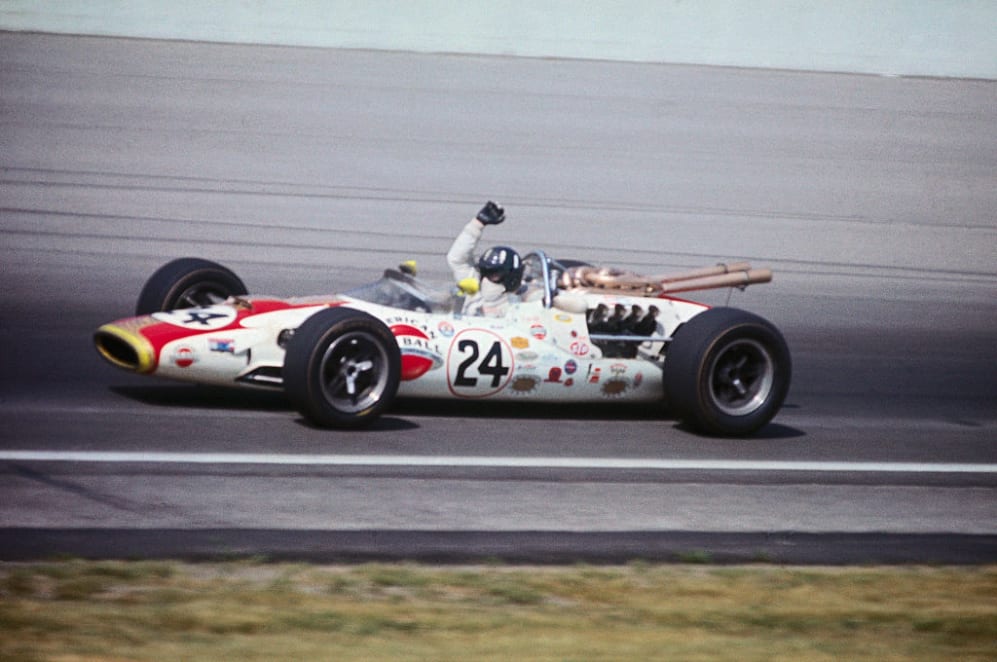 (Original Caption) Graham Hill, with arms raised in victory signal, circling track after winning