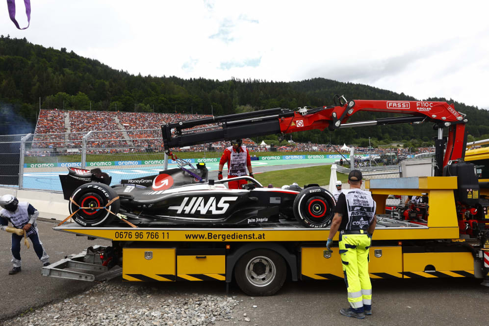Workers lift the car of Haas F1 Team's German driver Nico Hulkenberg off the track during the