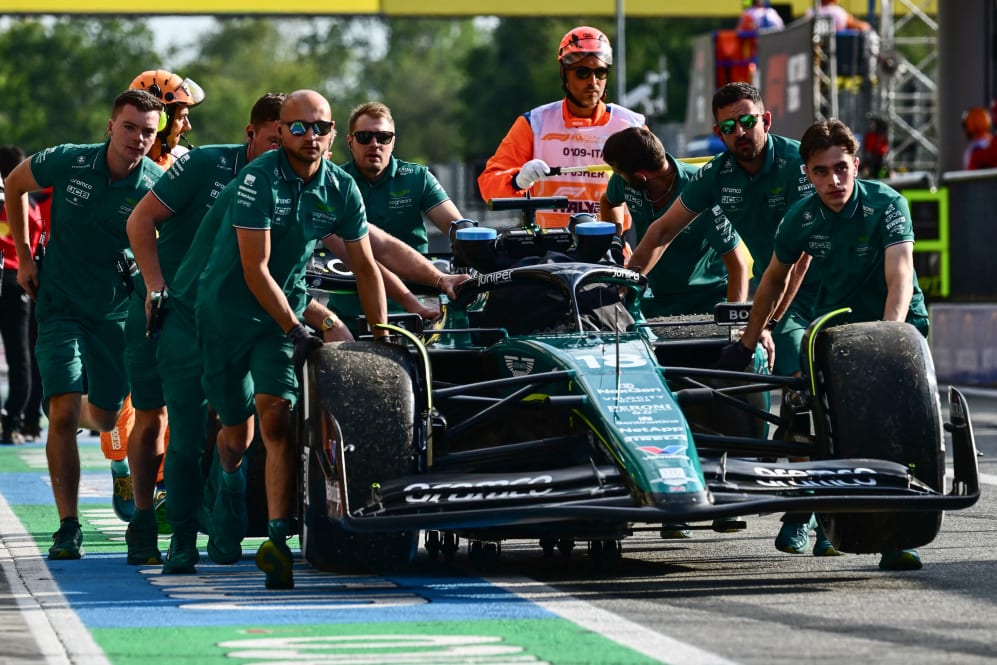 Mechanics run back Aston Martin's Canadian driver Lance Stroll's car in the pit area after a crash