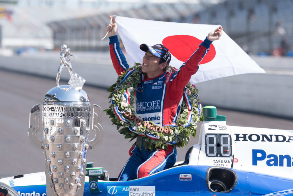 INDIANAPOLIS, IN - MAY 29: Takuma Sato holding up the Japanese flag with the Borg Warner Trophy
