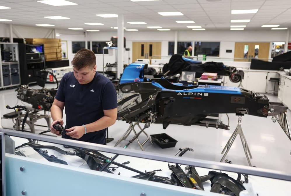 Un ingeniero trabaja en un coche de carreras de años anteriores dentro de la sede del equipo Alpine F1 Fórmula 1, en