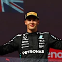 BUDAPEST, HUNGARY - AUGUST 03: Third placed George Russell of Great Britain and Mercedes AMG Petronas F1 Team on the podium with his trophy and Champagne during the F1 Grand Prix of Hungary at Hungaroring on August 03, 2025 in Budapest, Hungary. (Photo by Clive Rose/Getty Images)
