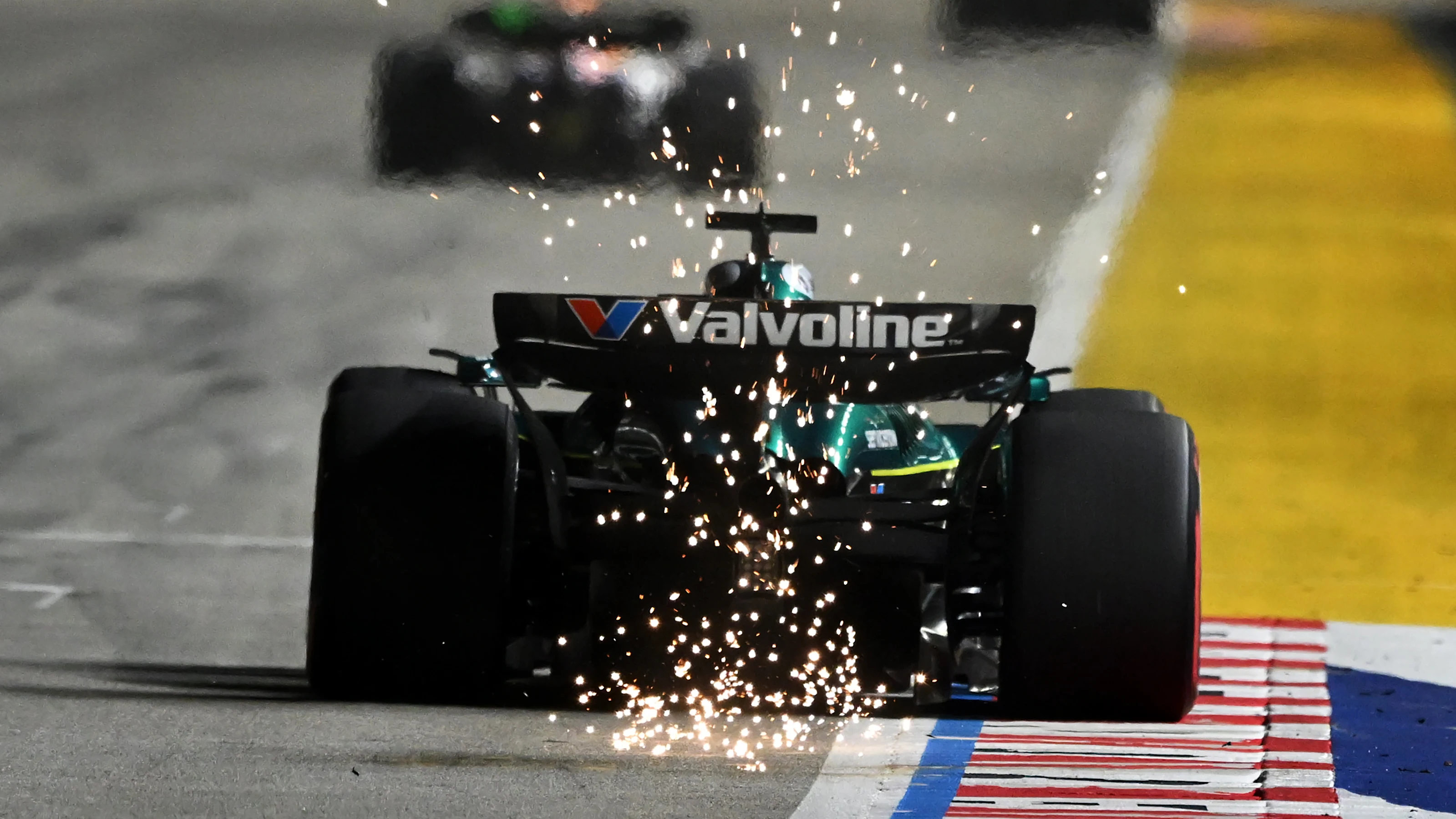 SINGAPORE, SINGAPORE - OCTOBER 05: Sparks fly behind Lance Stroll of Canada driving the (18) Aston
